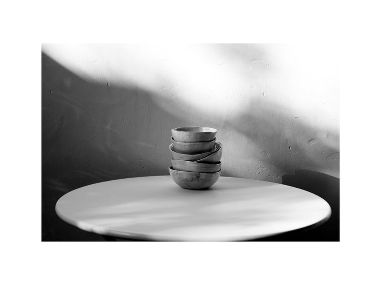 Cuencos de cerámica sobre mesa metálica con luces y sombras en blanco y negro