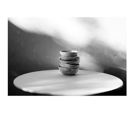 Cuencos de arcilla en una mesa redonda de metal con luces y sombras muy marcadas