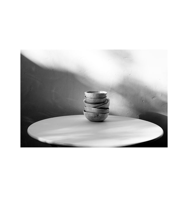 Cuencos de arcilla en una mesa redonda de metal con luces y sombras muy marcadas